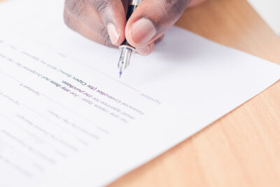 ¿Conoces la diferencia entre la escritura básica y la escritura de compraventa? 1 person signing on a contract